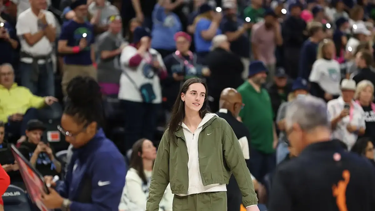 Caitlin Clark of the Indiana Fever in a white jersey dribbling the ball with her right hand