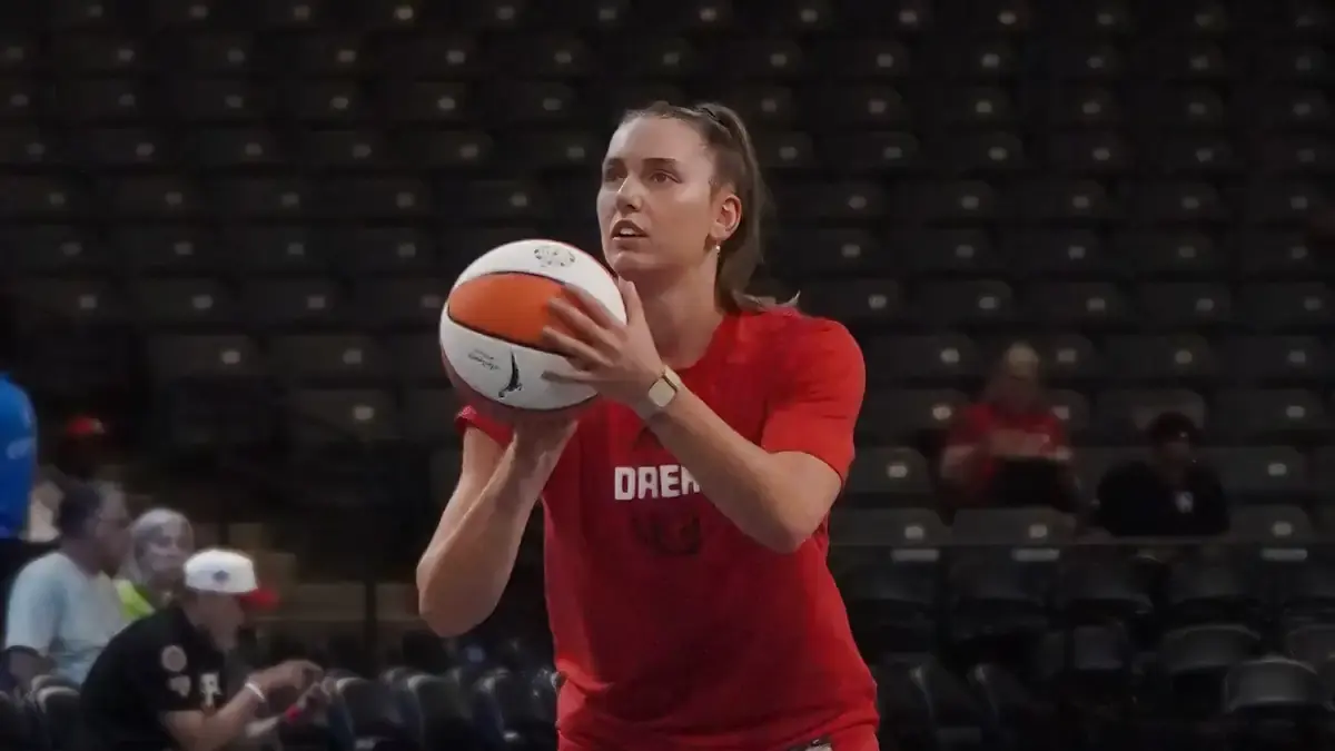 Isobel Borlase of the Atlanta Dream in a red Dream warmup shirt, holding a basketball before a shot