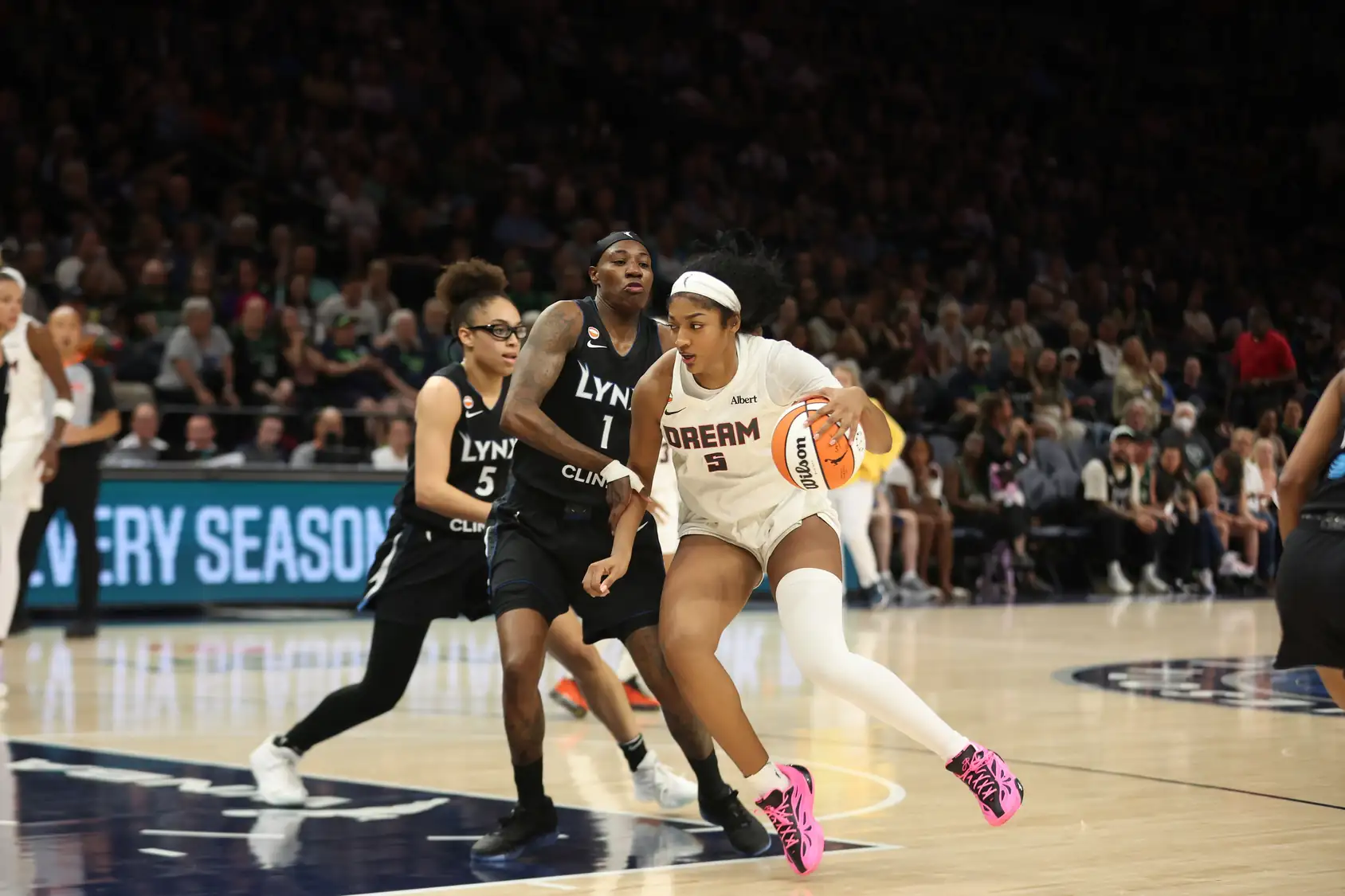 Angel Reese of the Atlanta Dream in a white number 5 road jersey with red trim holds a basketball and looks up